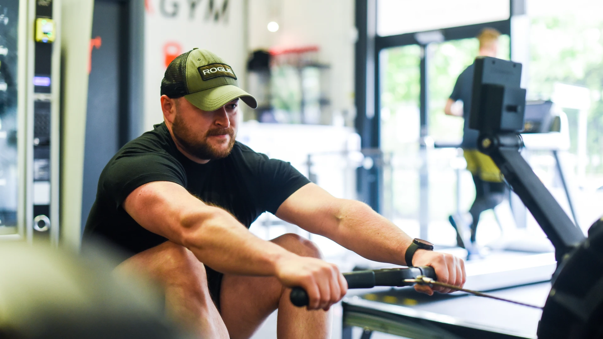 man with hat doing rowing on a machine