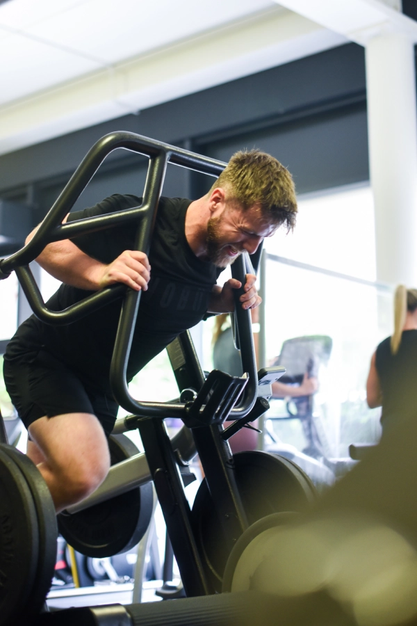 man with black shirt on gym machine for strenght training
